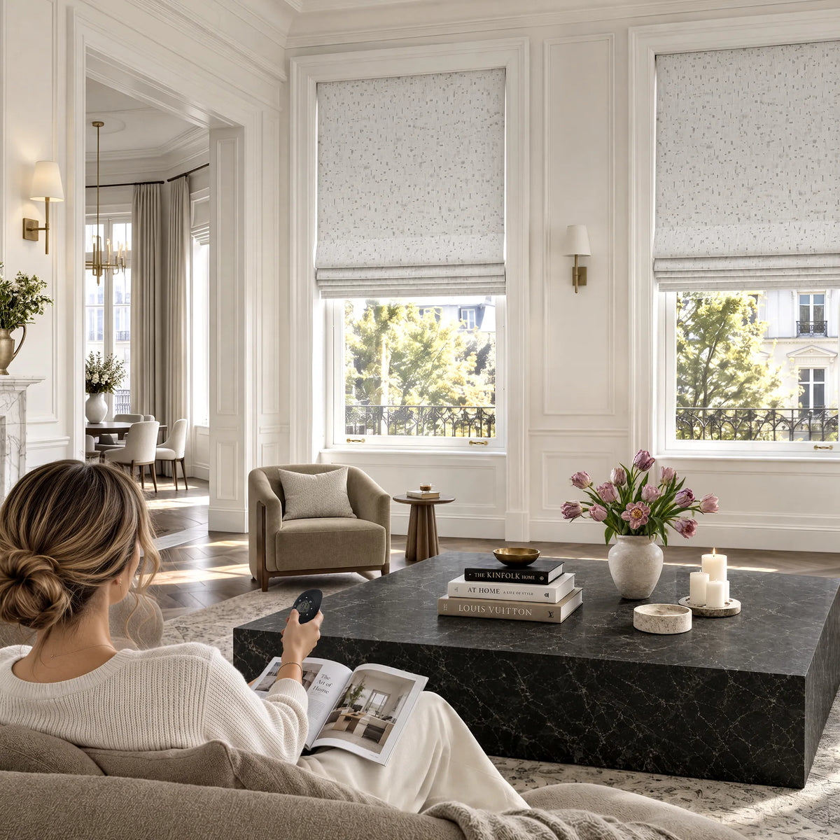 A person using a remote to adjust flat roman shades in a living room.