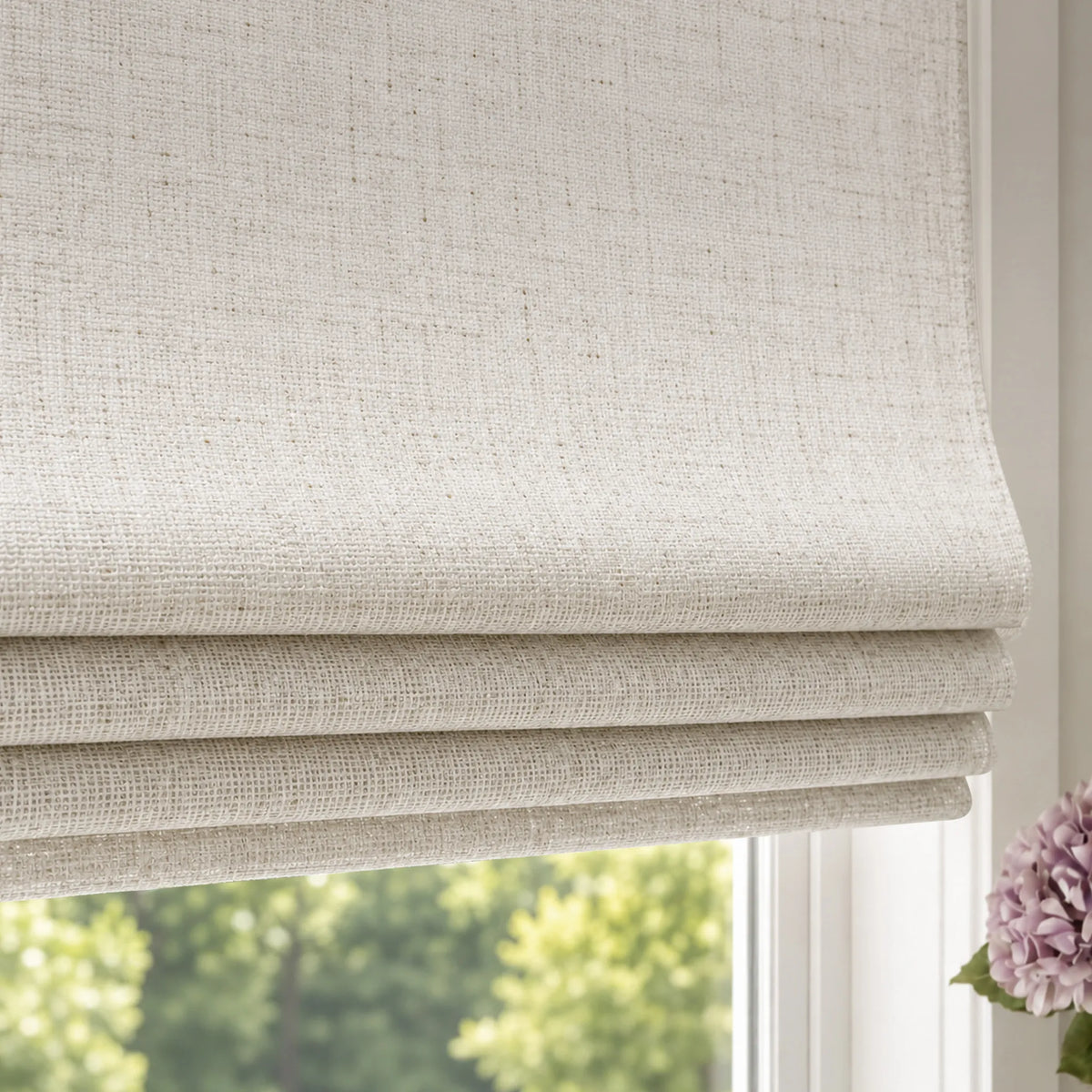 Close-up of light-colored textured flat roman shades with horizontal fabric folds.