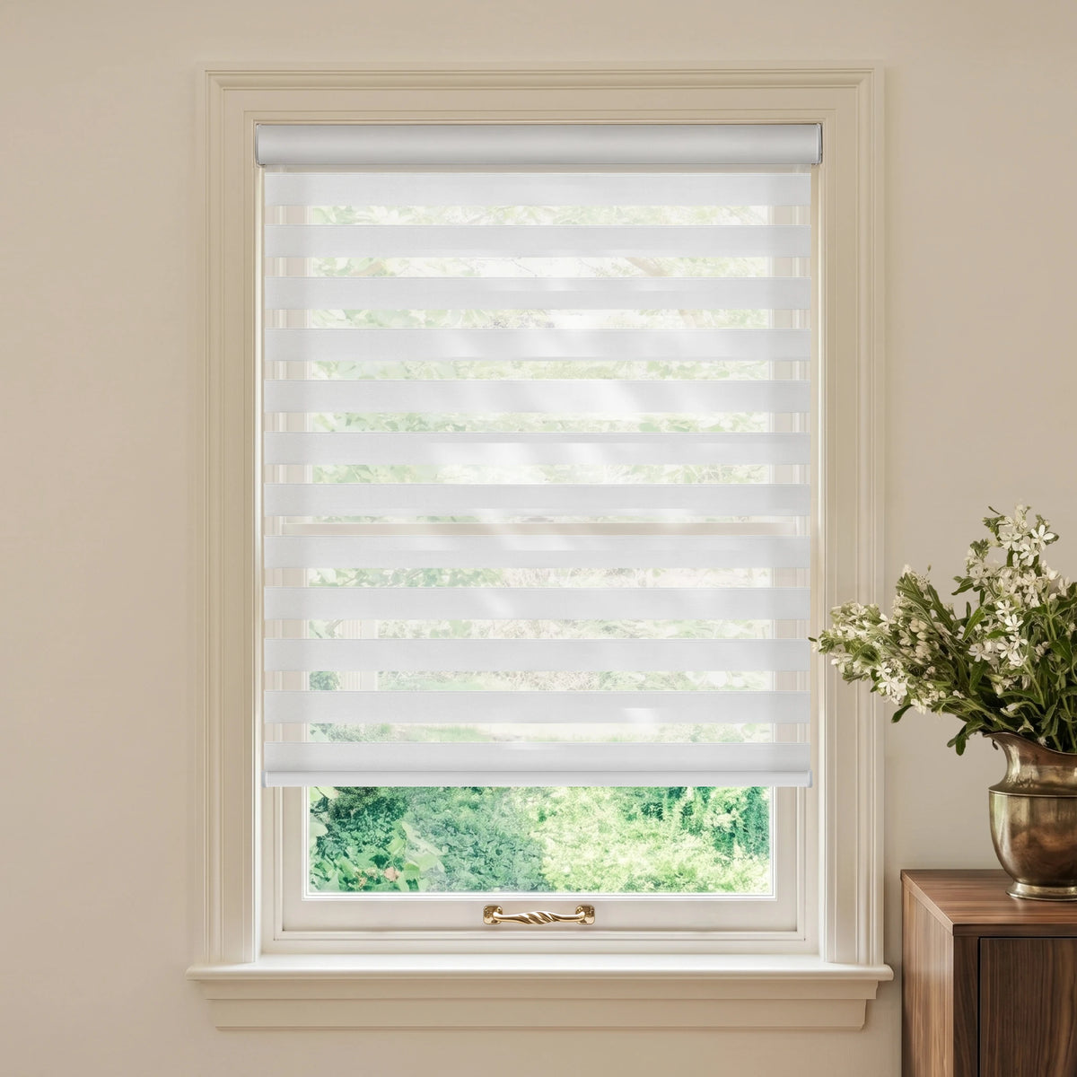 White motorized light-filtering zebra blind in a cream room beside a wooden table and white flowers.