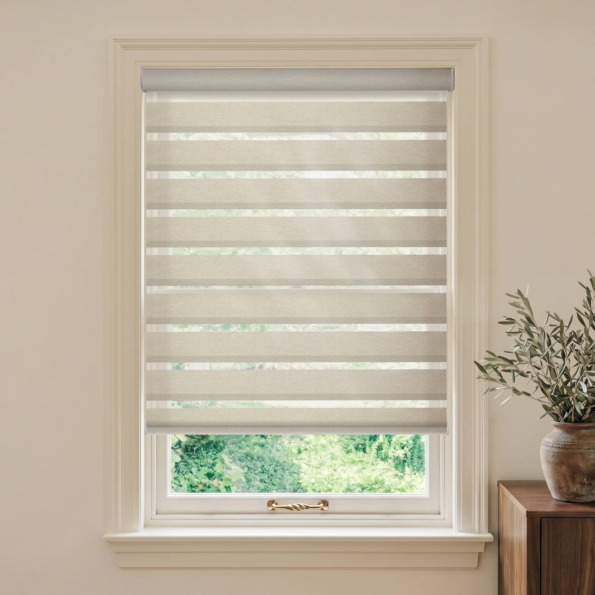 Coffee motorized room-darkening zebra blind in a warm room beside a wooden table and olive branches.