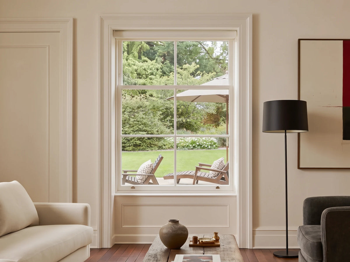 Graywind roller shade raised to reveal a living room window and garden view.