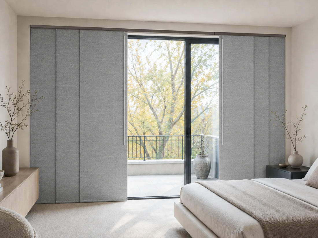 Gray fabric sliding window curtains installed on a glass patio door in a modern, minimalist bedroom.