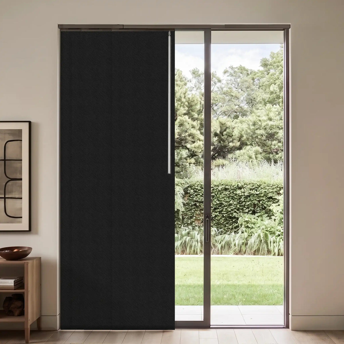 A black sliding door panel installed in a glass sliding door, shown in a modern interior setting with a garden view.