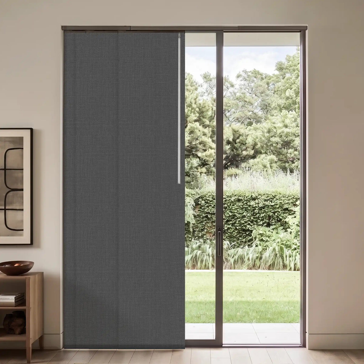 A dark gray textured sliding door panel installed in a glass sliding patio door, set in a modern interior with a light wood floor and a side table.