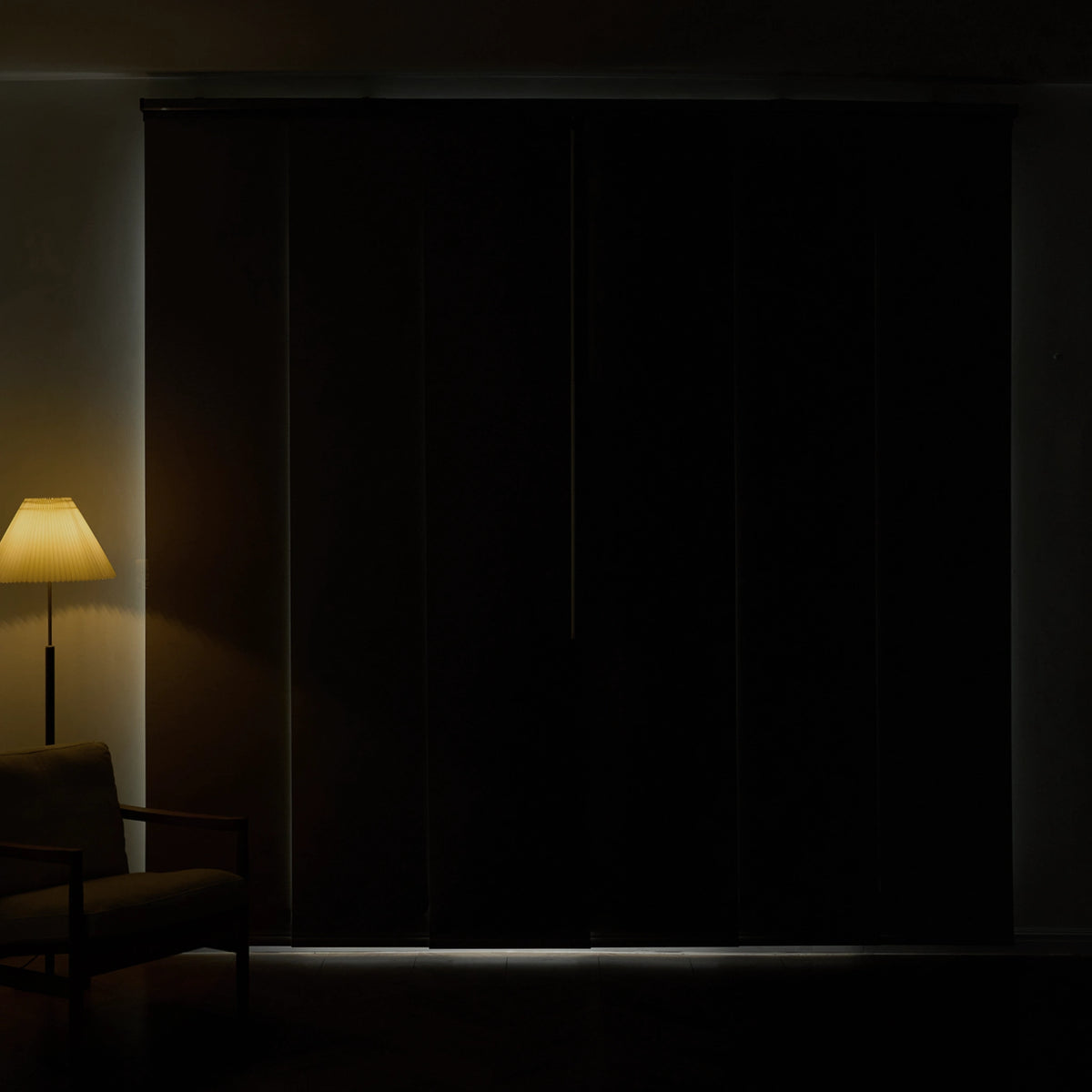 blackout panel track blinds fully closed in a dark room with only a small line of light at the floor