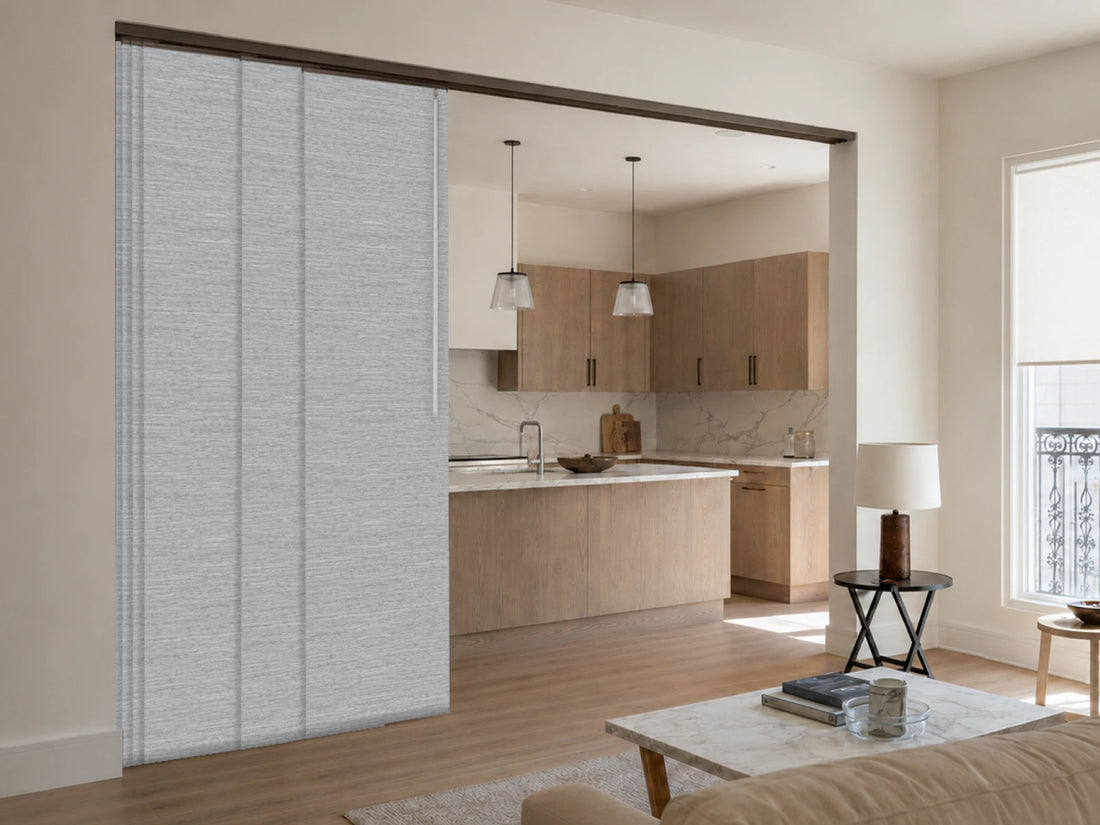 A pair of light gray textured sliding door panels installed in a doorway of a modern living room and kitchen.