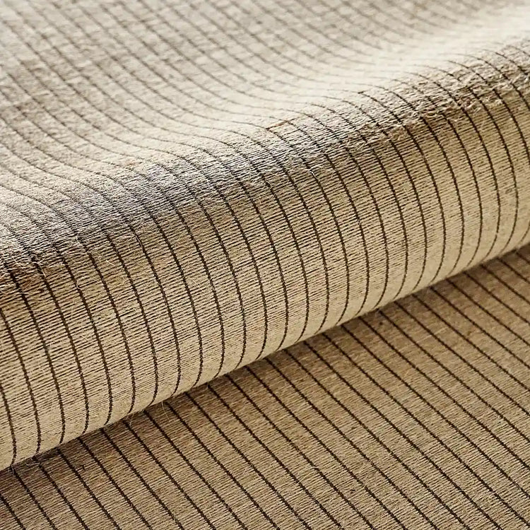A close-up of woven fabric with a beige base and thin dark brown vertical stripes, shown folded to highlight the texture and pattern.