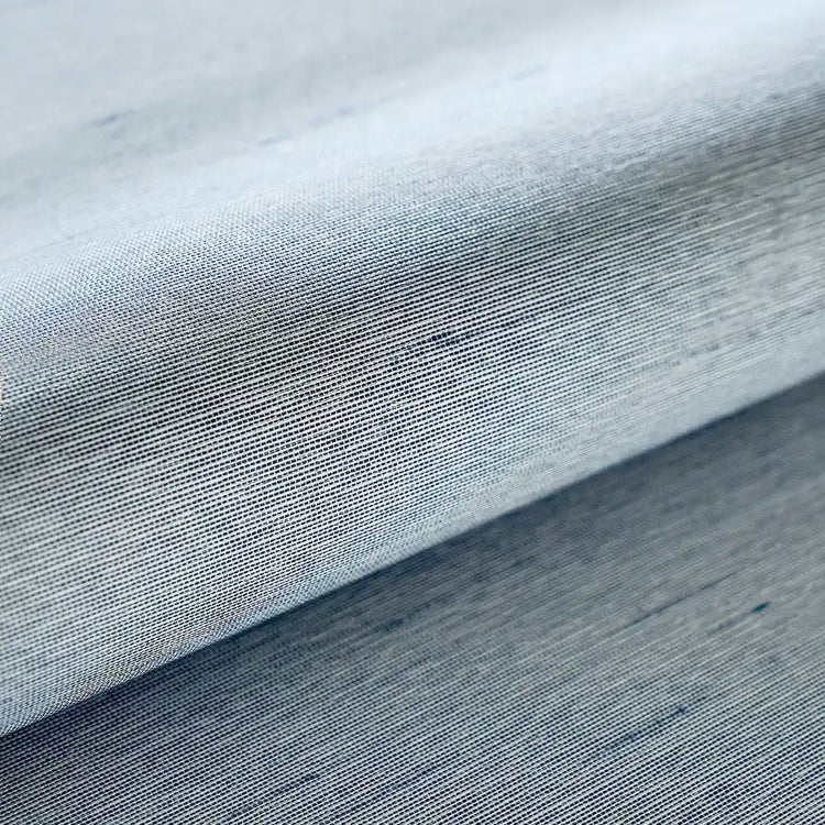 A close-up of light blue-gray woven fabric with a fine textured weave, shown folded to highlight its material and color.