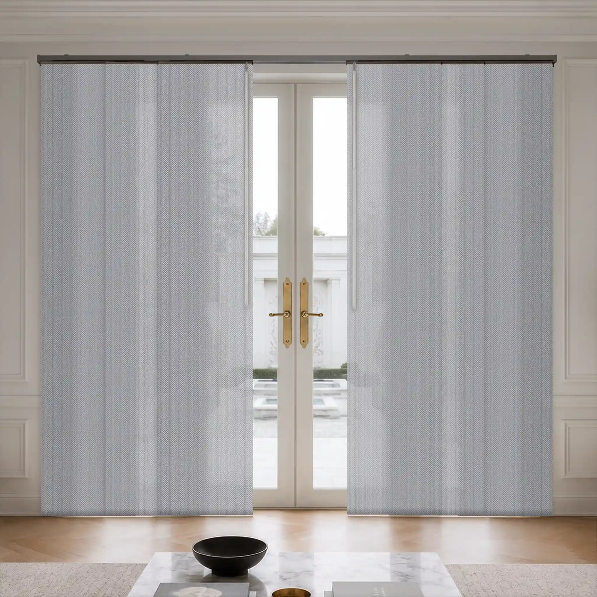 Light blue textured panel curtains hanging on a black rod over a glass door in a bright, modern room.