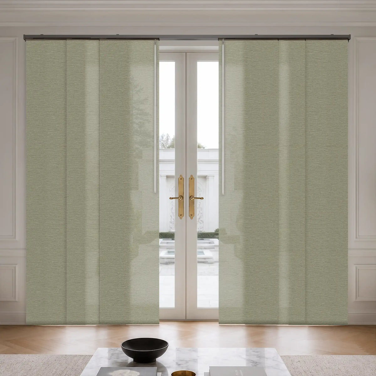 A pair of light sage green textured panel curtains hanging on a black rod over a set of white double glass doors in a bright, modern room.