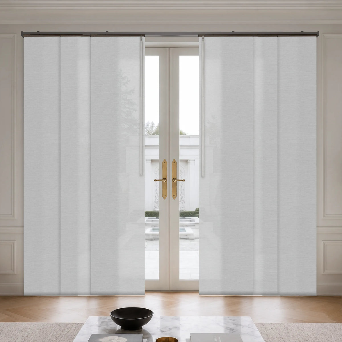 White sliding patio door curtains installed on a glass double door in a bright, modern room with light wood floors and gold handles.