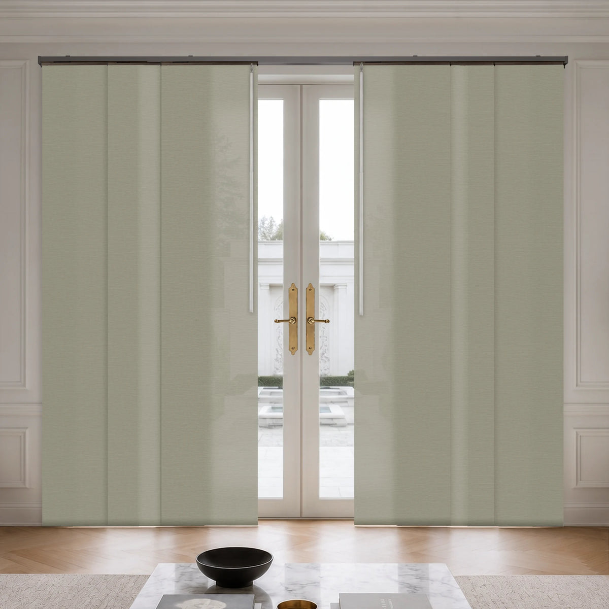 A pair of light sage green roller curtain panels partially drawn to the sides of a white double glass door, set in a bright, modern room with a marble coffee table and wooden floor.