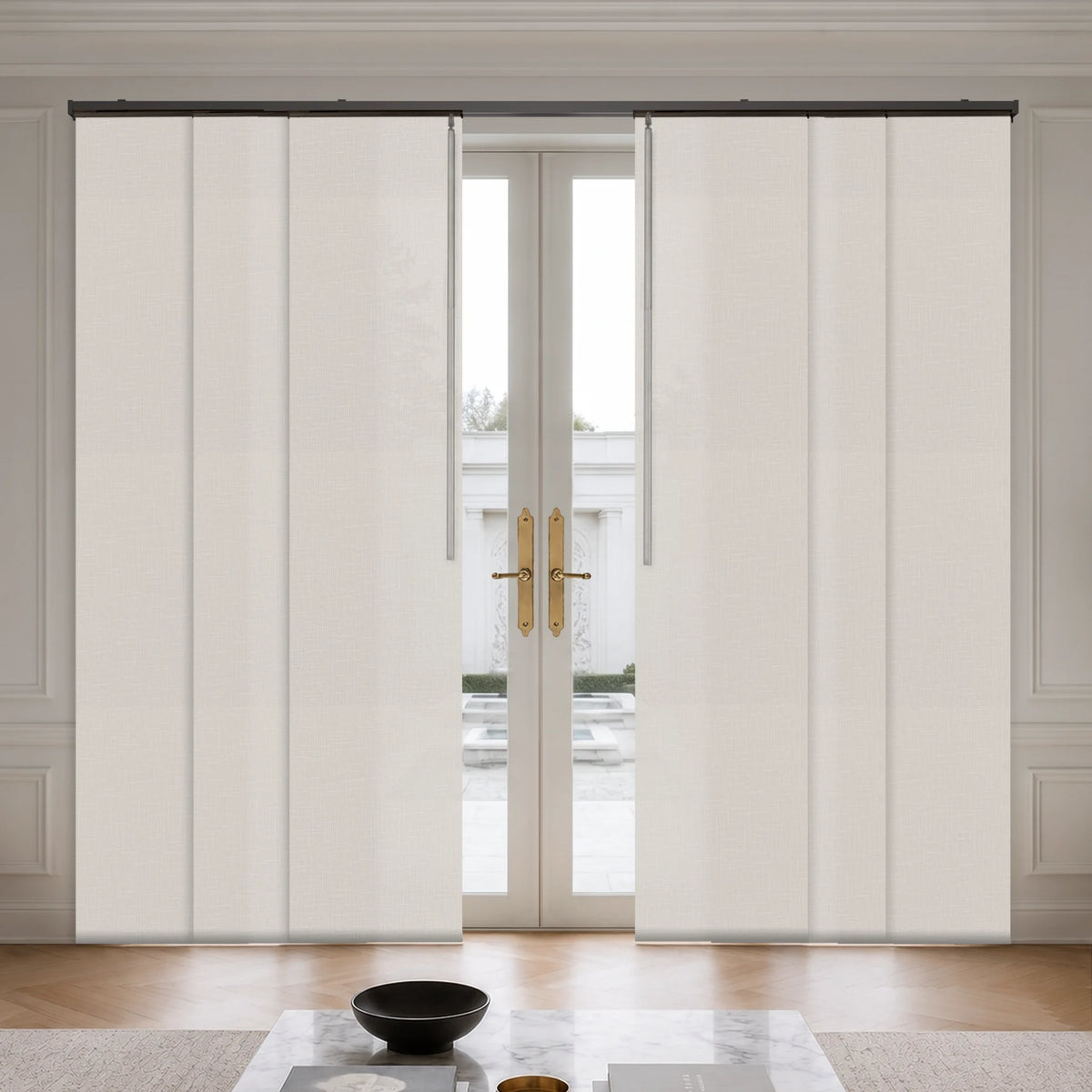 A pair of cream-colored, vertically pleated sliding patio curtains shown installed on a track system flanking a set of double glass doors in a bright, modern room.