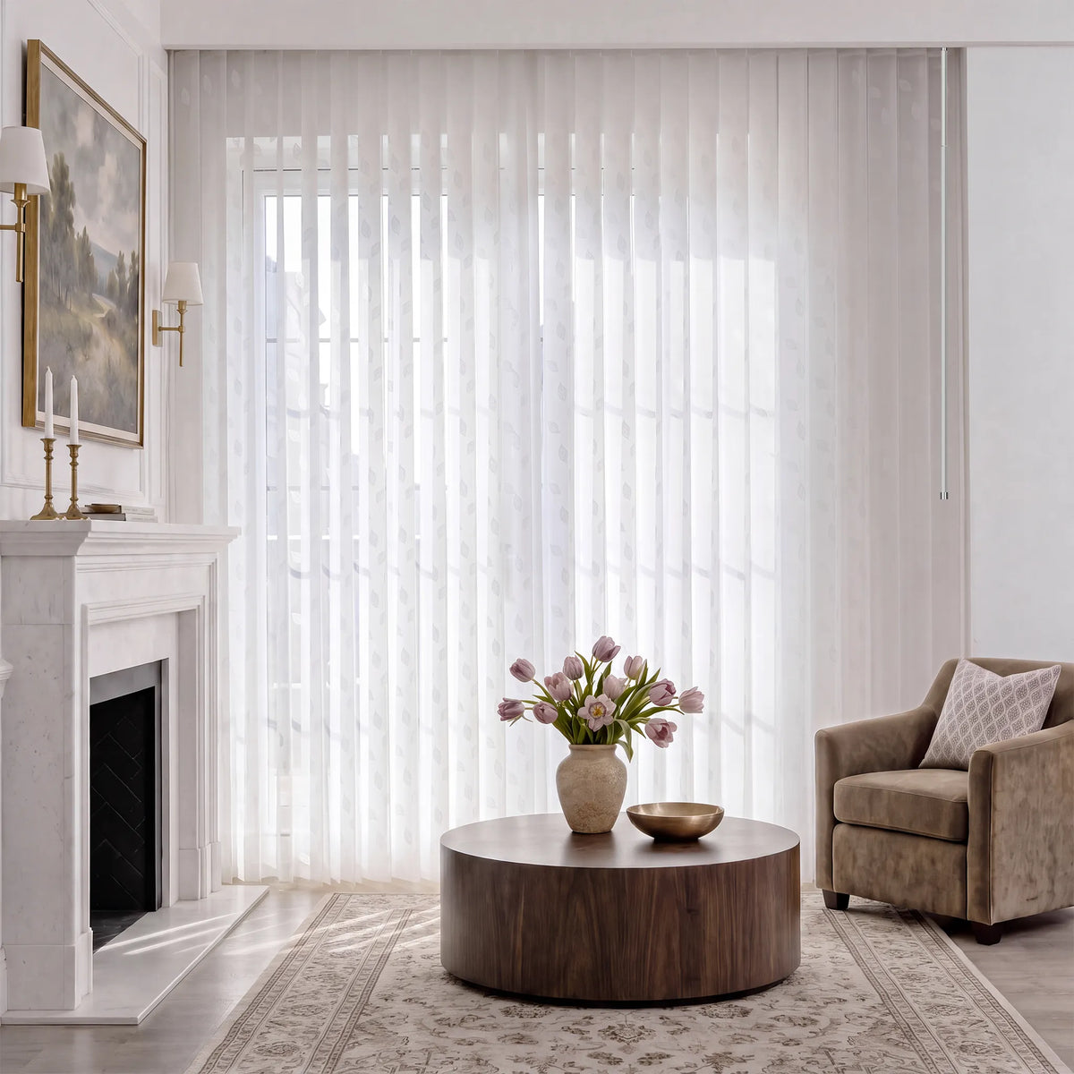 A living room scene with white manual Sheer Vertical Blinds covering a large window, styled with a wooden sideboard, chairs, a round mirror, and a vase of tulips on the table.