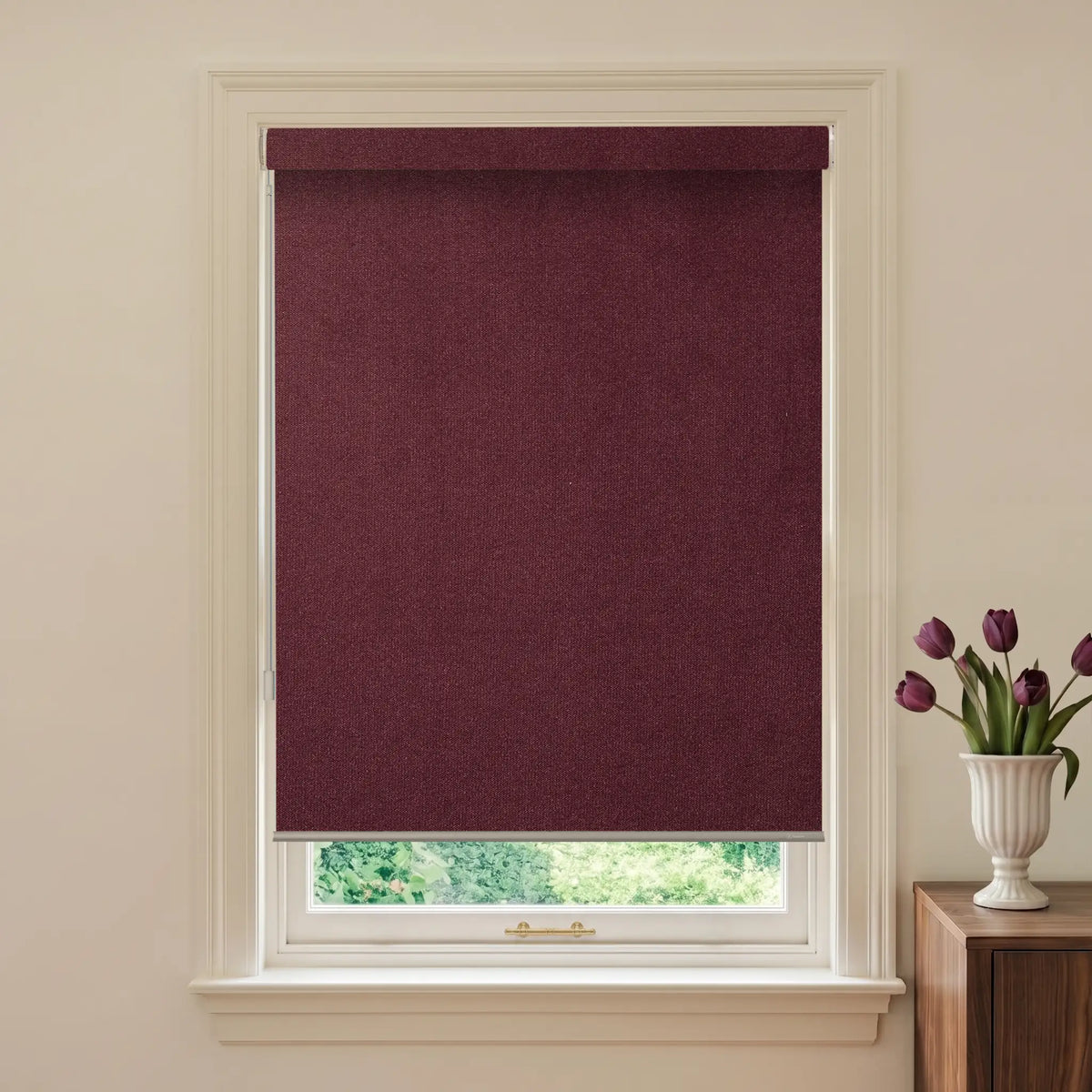 Window with a purple roller blind and a vase of tulips on a wooden cabinet.