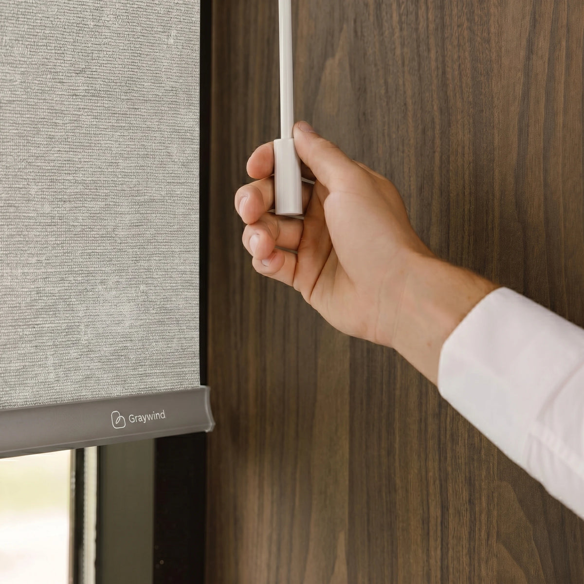Hand adjusting a motorized roller shade on a wooden door