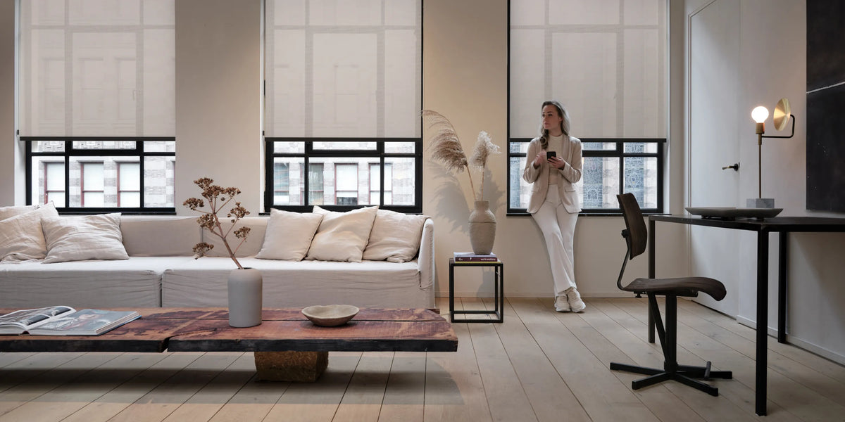 Modern living room with a woman standing near a motorized roller shades