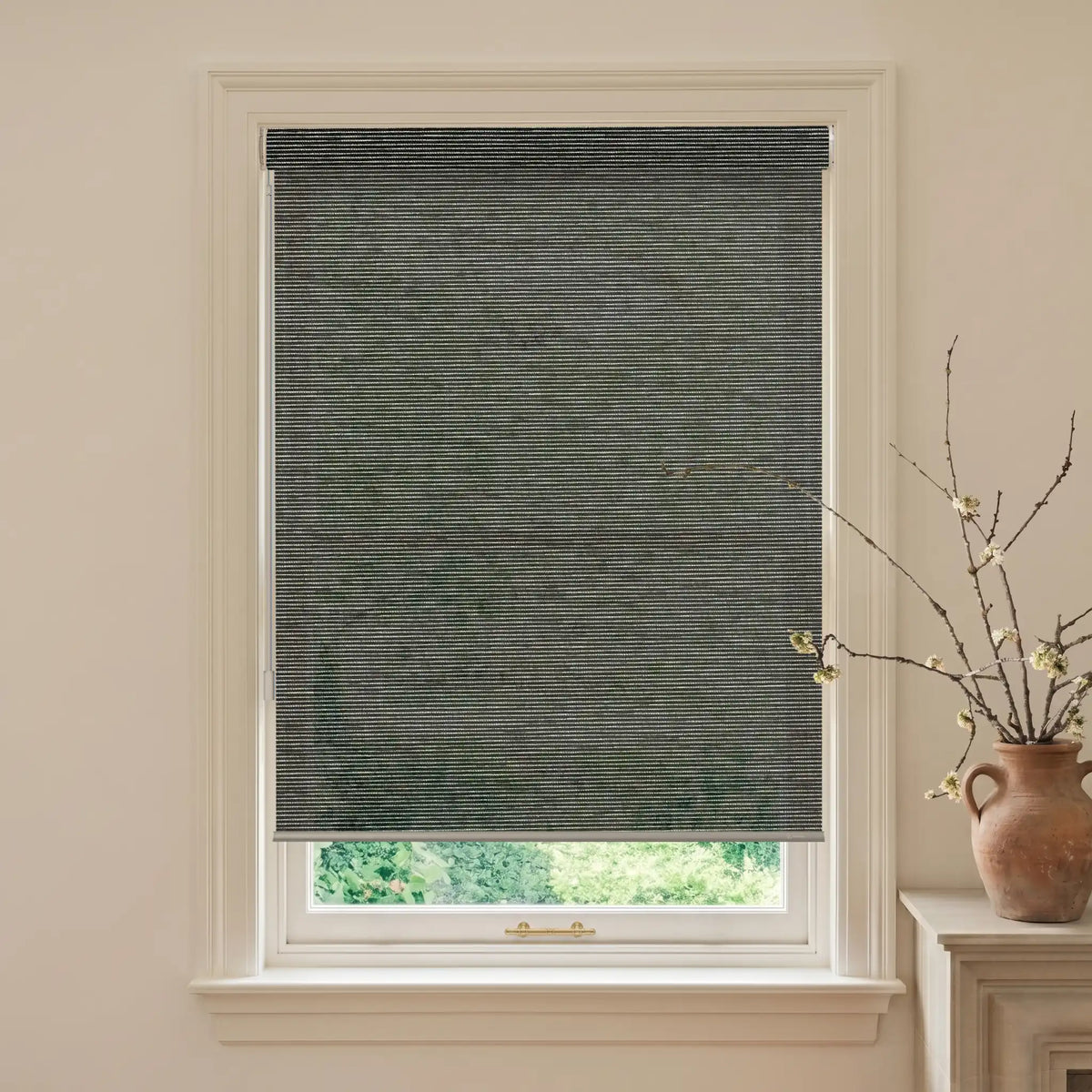 Window with a dark gray roller blind, light-colored walls, and a vase with branches on a windowsill.