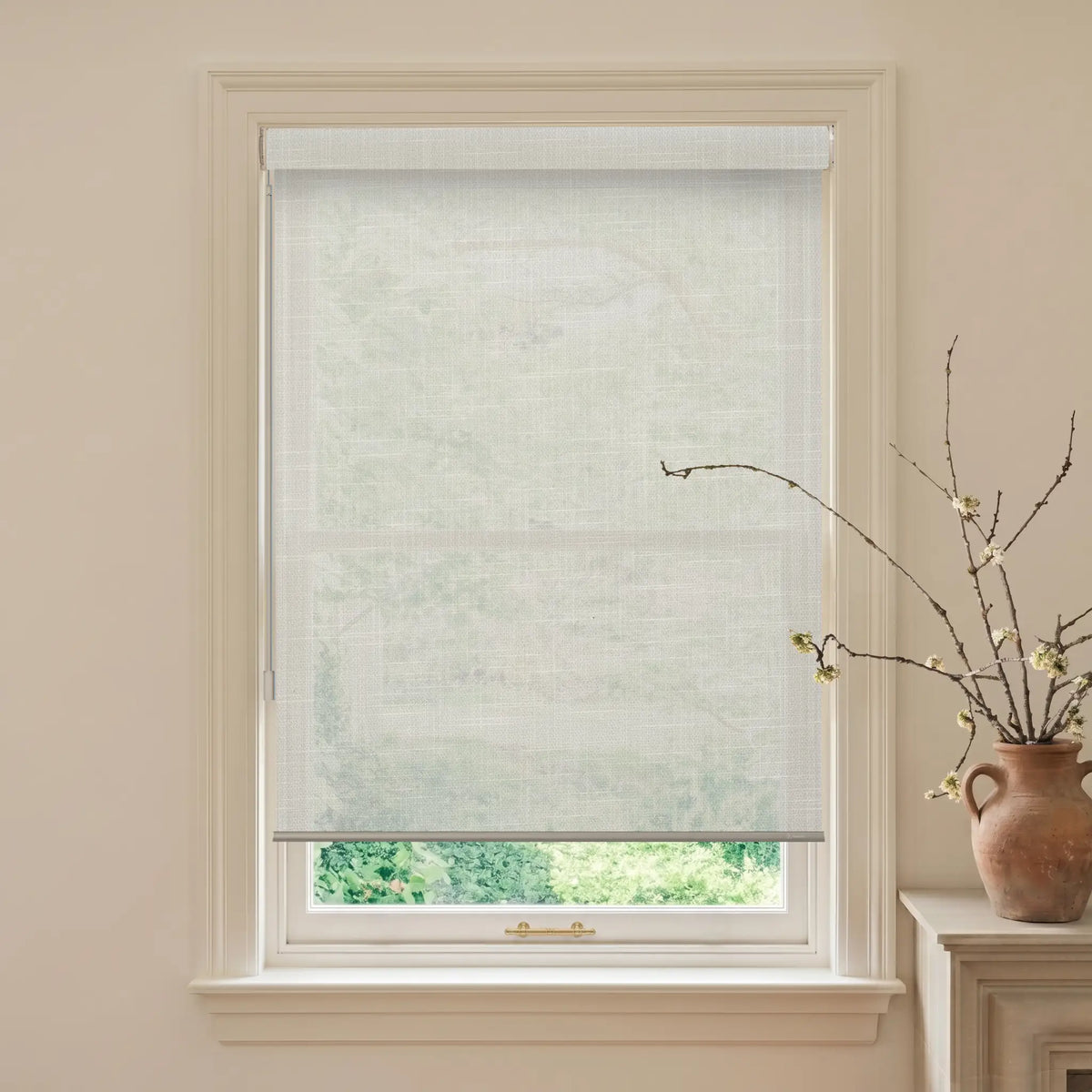 Window with a roller blind and a vase with branches on a windowsill.