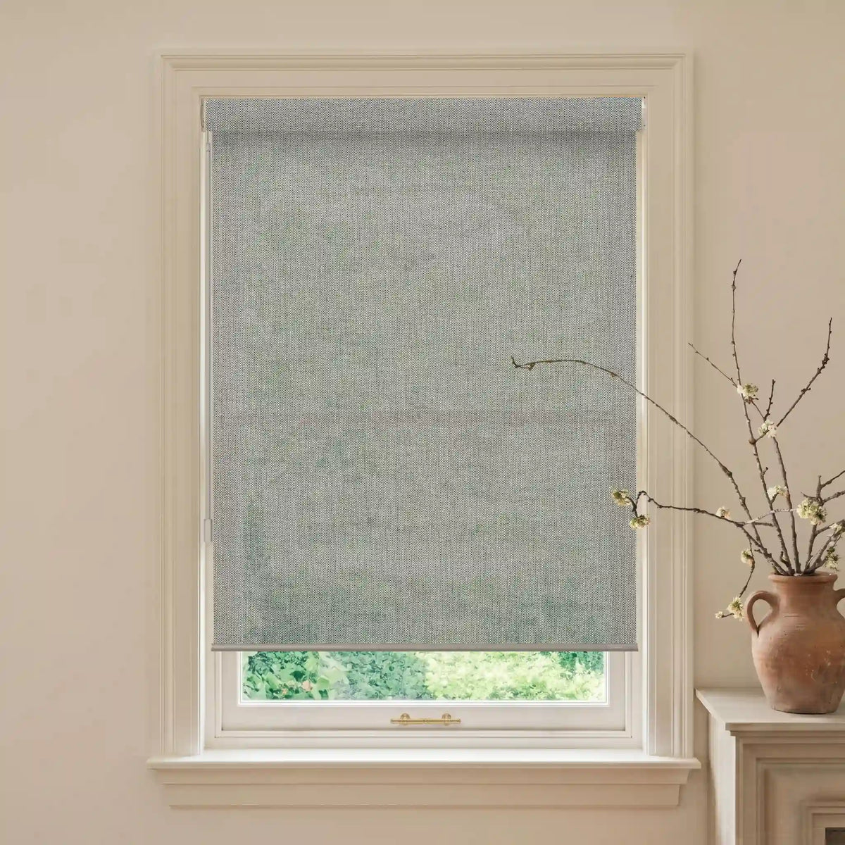 Window with a gray roller blind, light-colored walls, and a vase with branches on a windowsill.