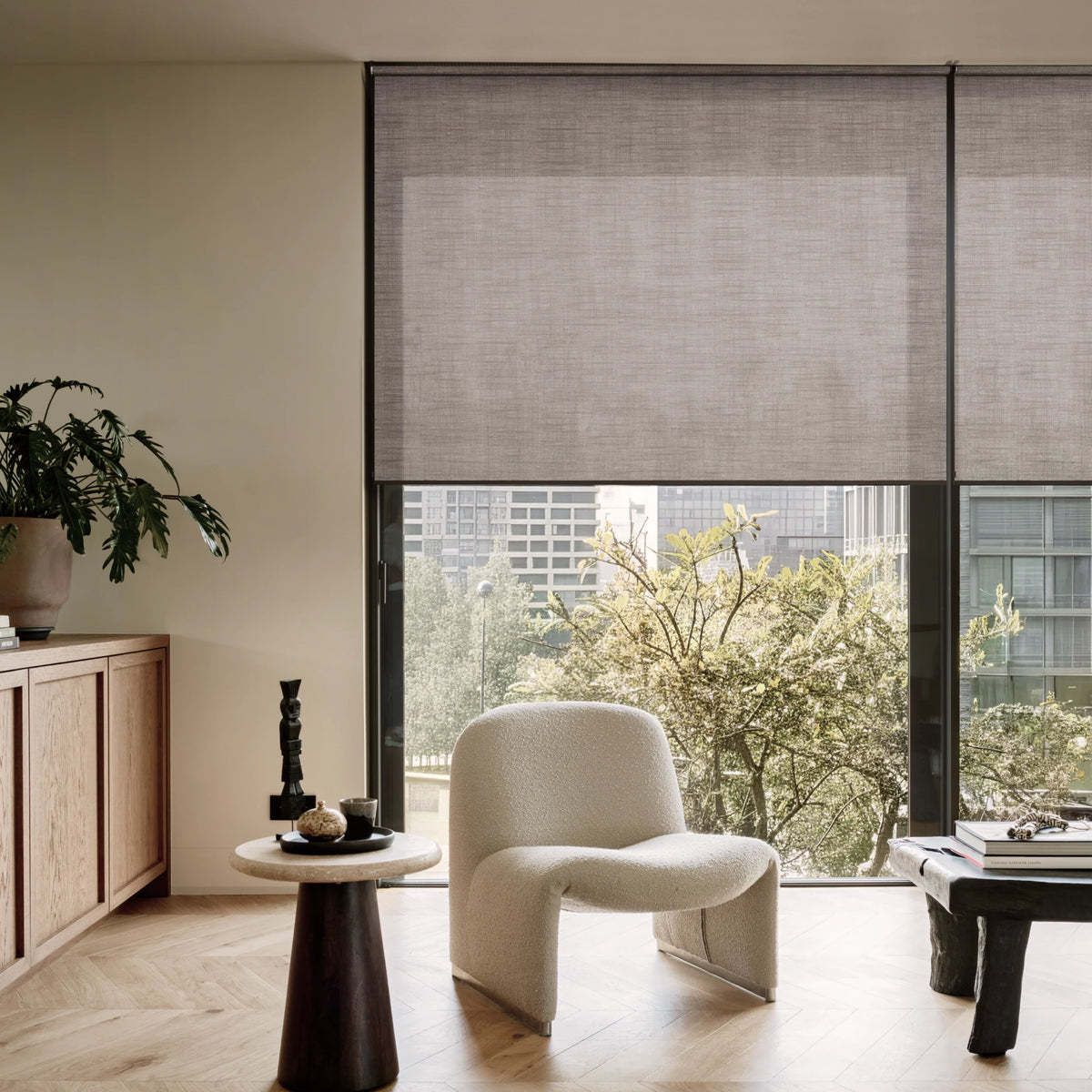 Modern interior with a wooden table and chairs in front of large windows with smart shades.