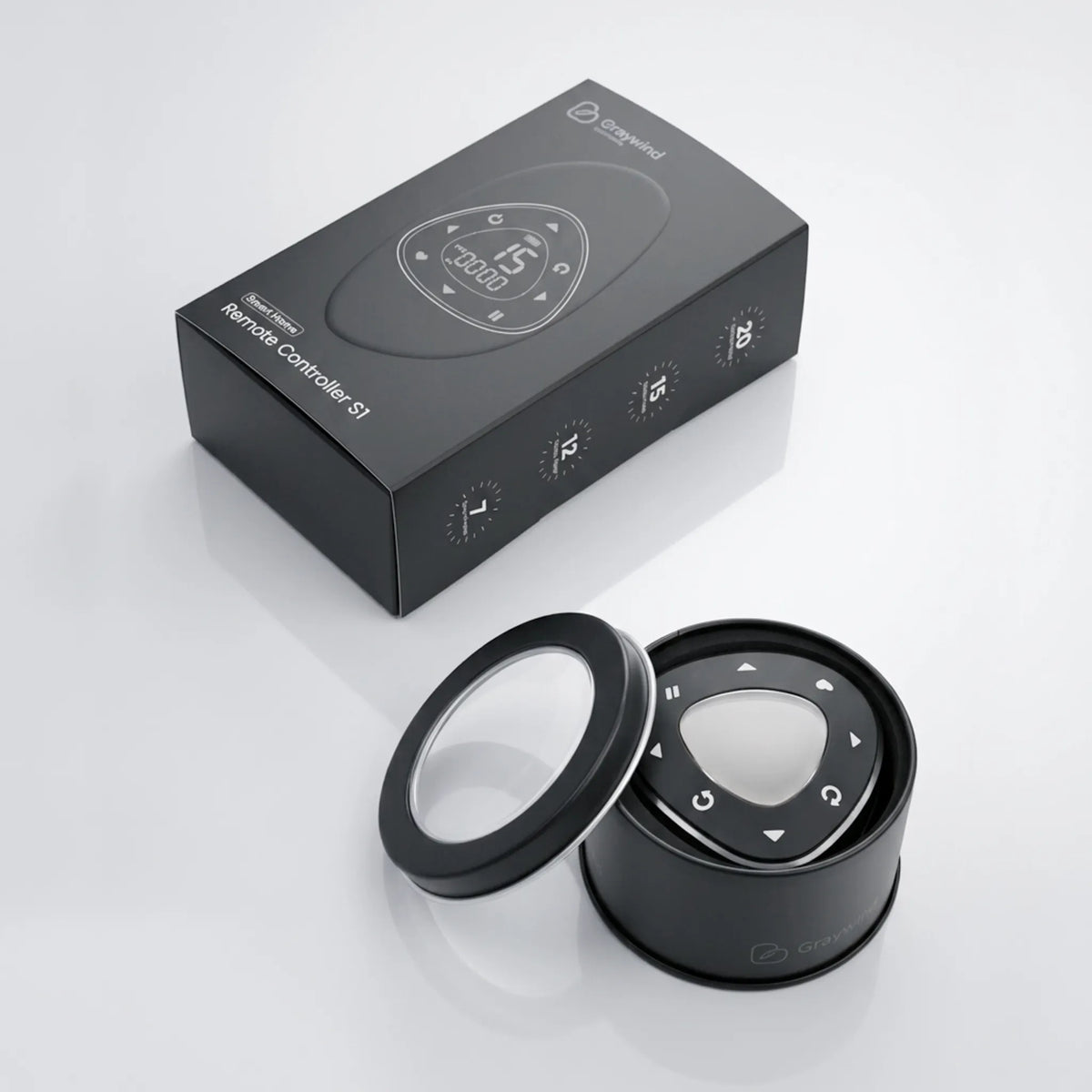 A black remote control box and a matching black remote control with a circular display and control buttons, shown on a clean light gray reflective surface.