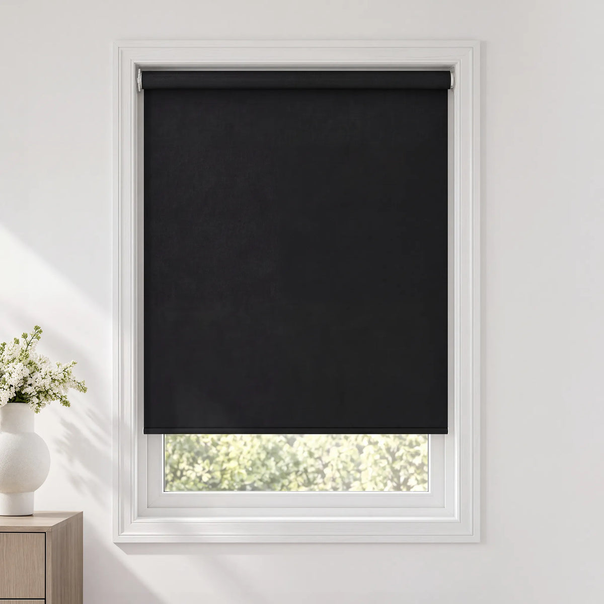 A motorized no-drill roller shade with a white frame installed on a window in a bright, modern room.