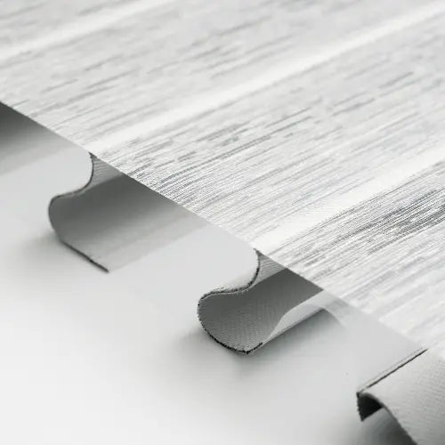 Close-up of a corrugated sheet material with a light gray woodgrain texture and ribbed edges, shown against a white background.