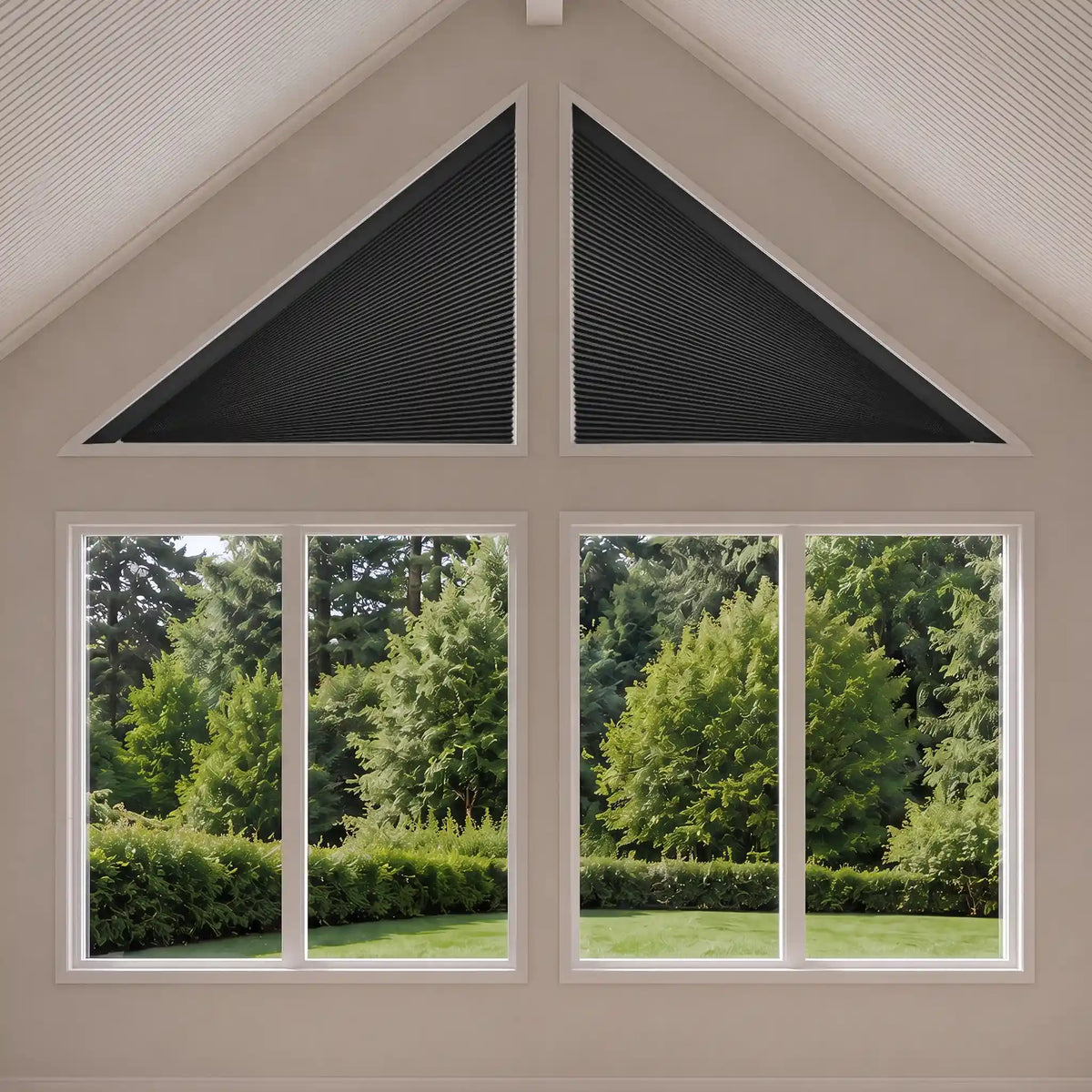 Black triangular cellular shade window blinds installed on the gable ends of a white-framed window, showing a green garden view outside.