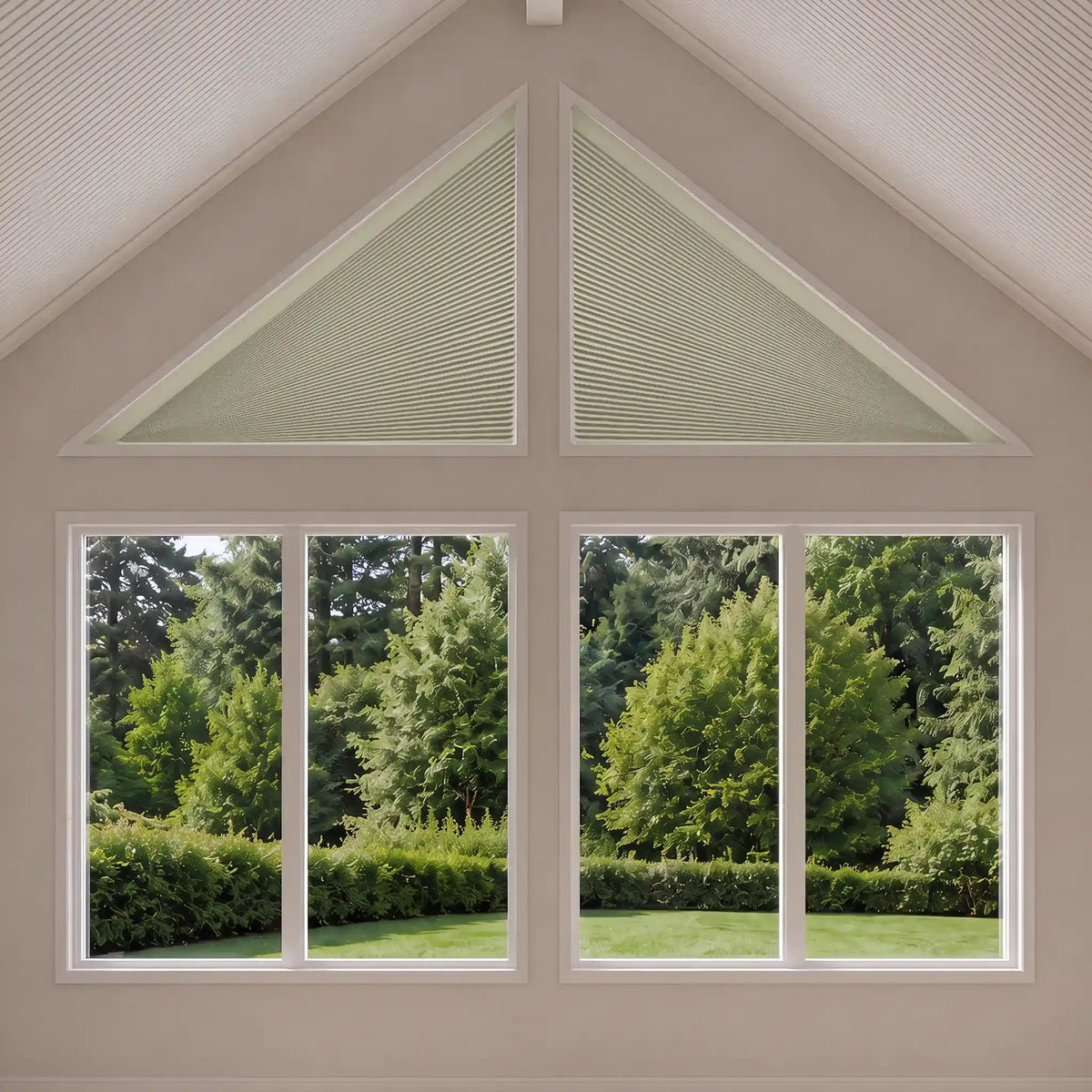 Two large triangular window shades installed above a four-pane window, showing a green garden outside. The room has beige walls and a white gabled ceiling.