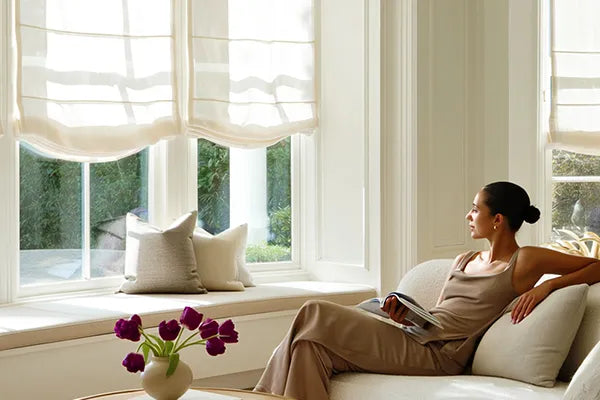 Woman relaxing beside custom Roman shades in a bright modern living room