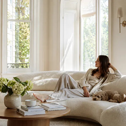 Woman relaxing in a sunlit home with soft custom window treatments