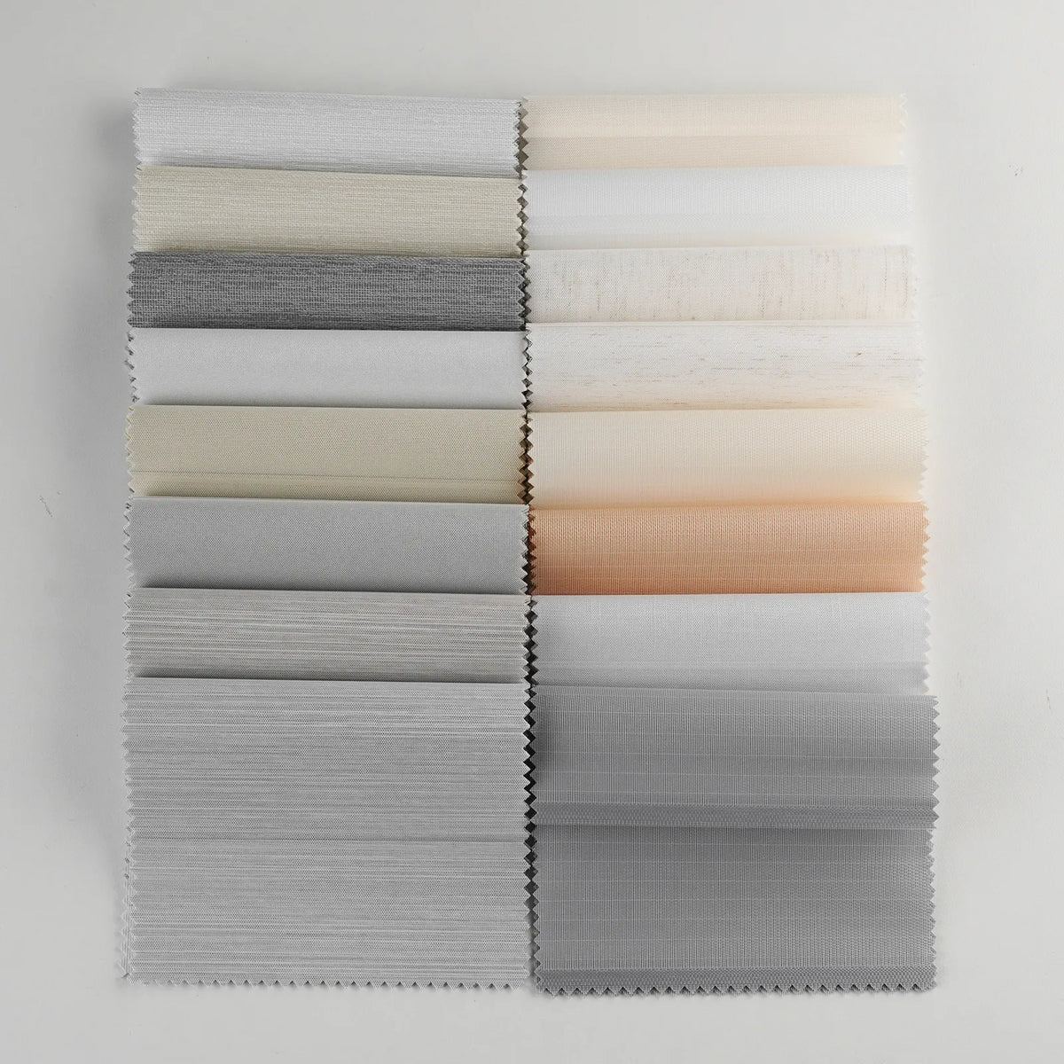 A set of fabric swatches arranged in two vertical columns on a plain white background. The swatches include various shades of gray, off-white, beige, and a soft peach tone, with some showing a subtle wood grain texture.