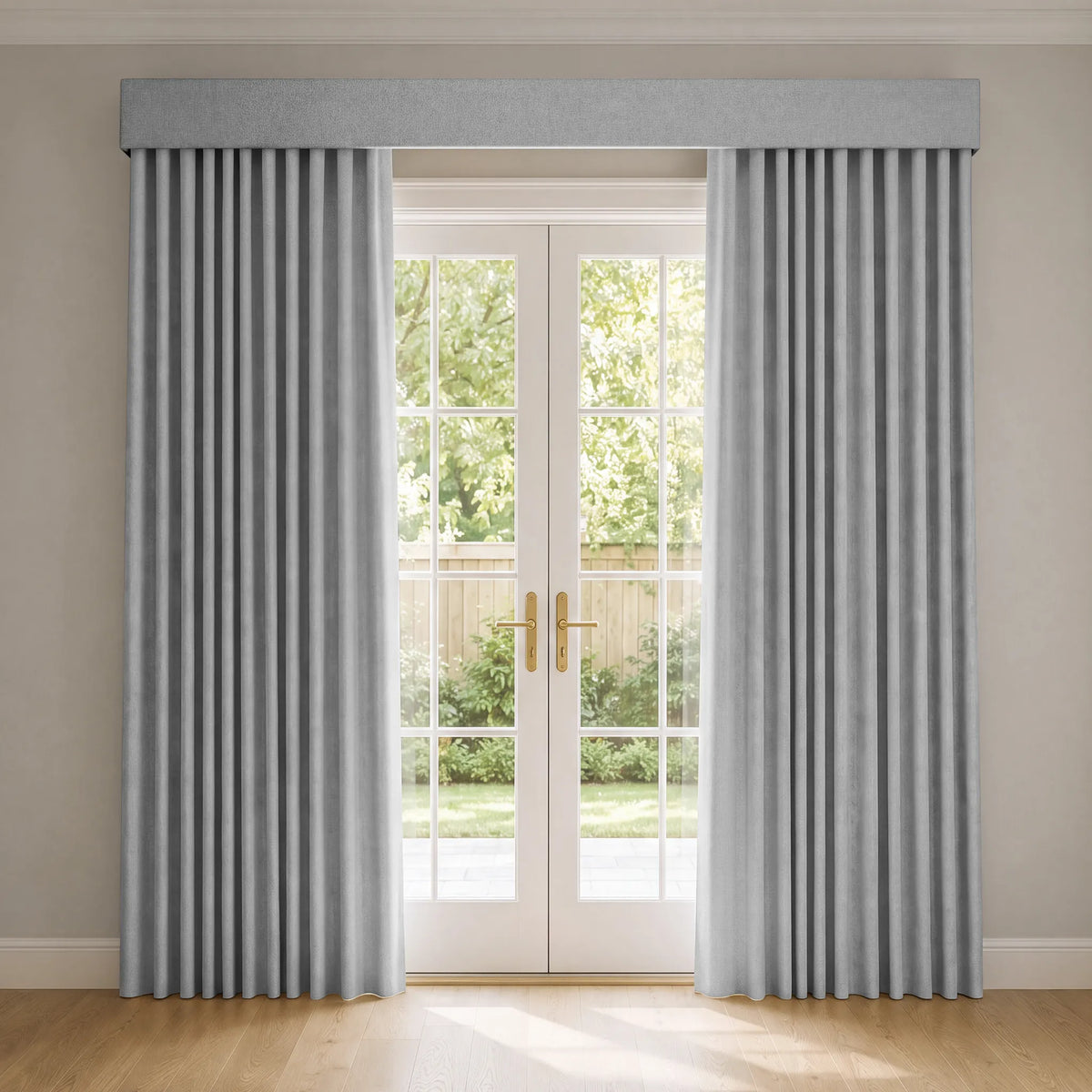 Light gray pleated curtains with a matching fabric valance hanging on a double glass patio door in a bright room with light wood floors.