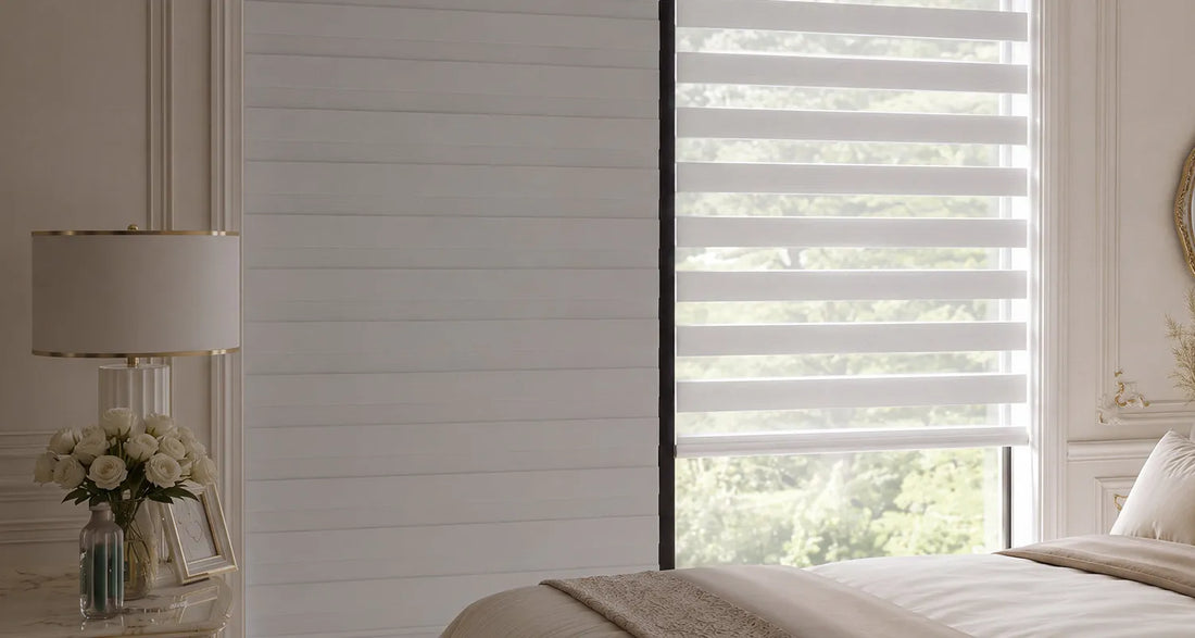 White horizontal zebra blind shown installed on a window in a beautifully decorated bedroom with a bed, bedside table, and lamp.