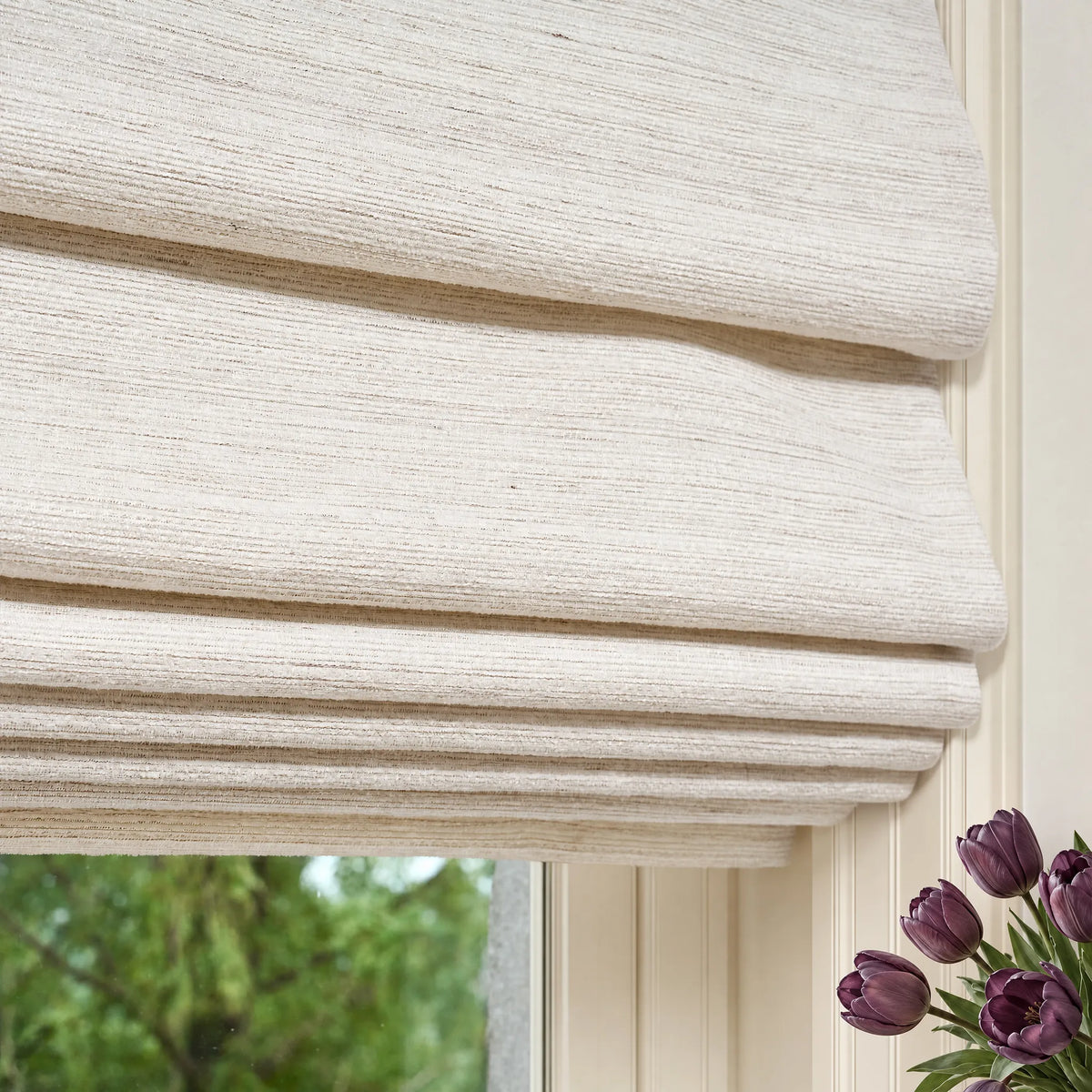 Close-up of soft fold Roman shades showing light-colored textured fabric and cascading folds.