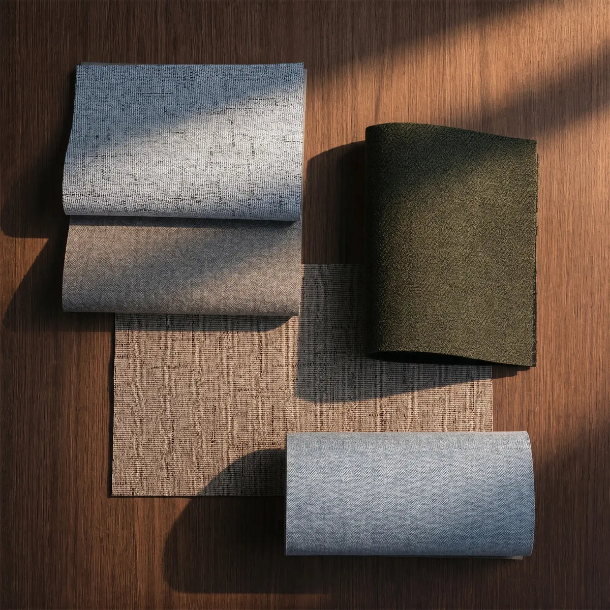 Four rolls of fabric in different colors on a wooden surface