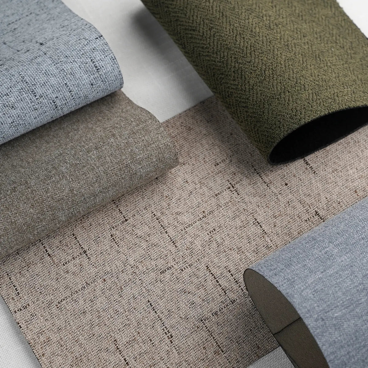 Rolls of textured fabric in various colors on a white background