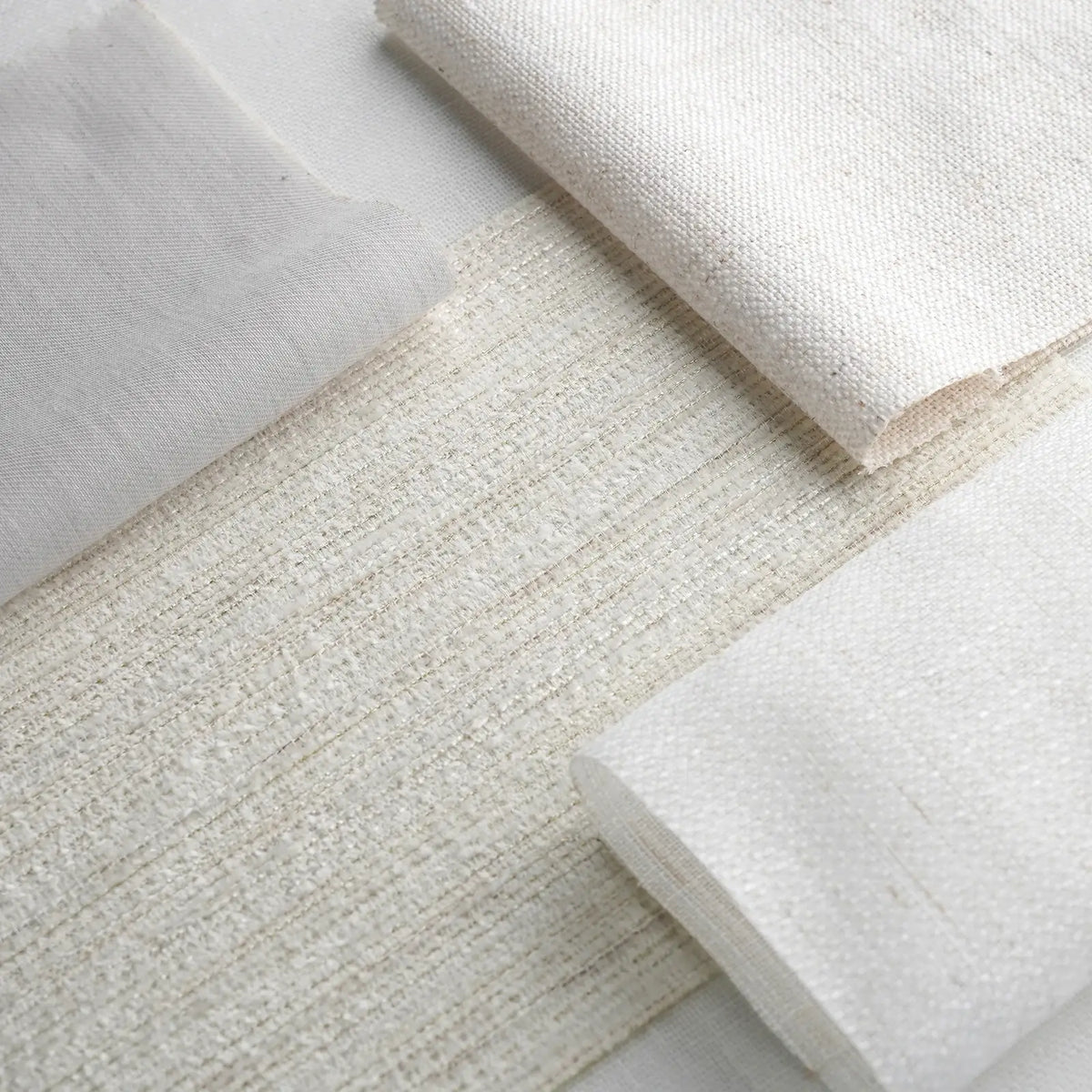 Close-up of various textured white fabrics on a light gray background