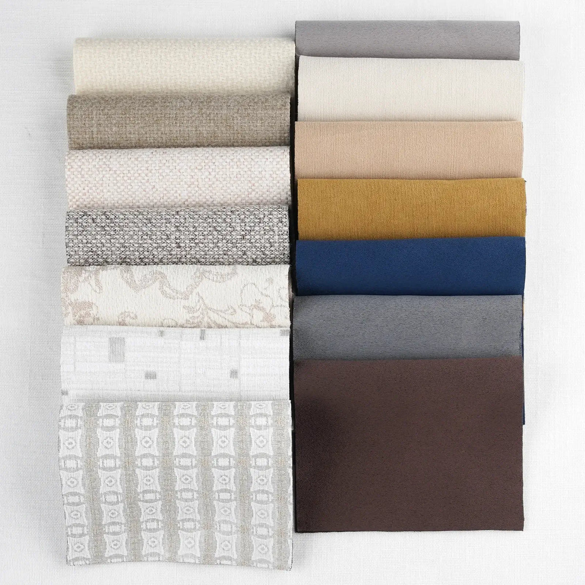 Collection of folded fabric swatches in various colors and patterns on a white background